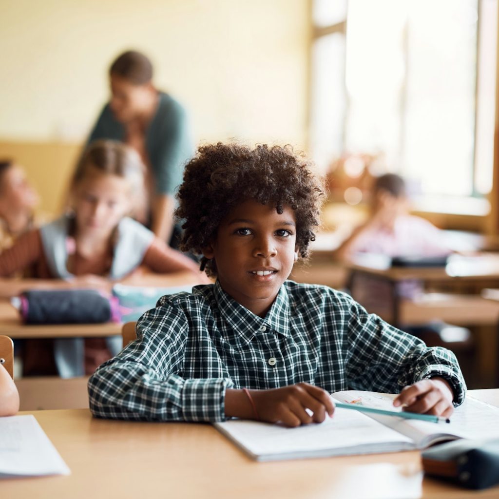 Happy black elementary student in the classroom looking at camera.