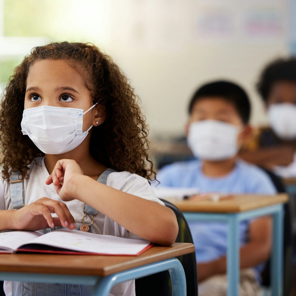 School student with covid learning in class, wearing mask to protect from virus and looking concent